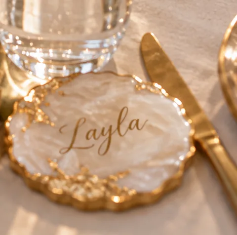 A pearl and gold name coaster reading Layla, used as a place card